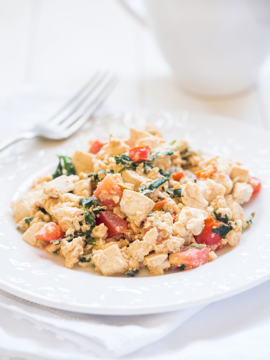 Vegan tofu scramble with tomato and green herbs. White background, vertical orientation, close up.