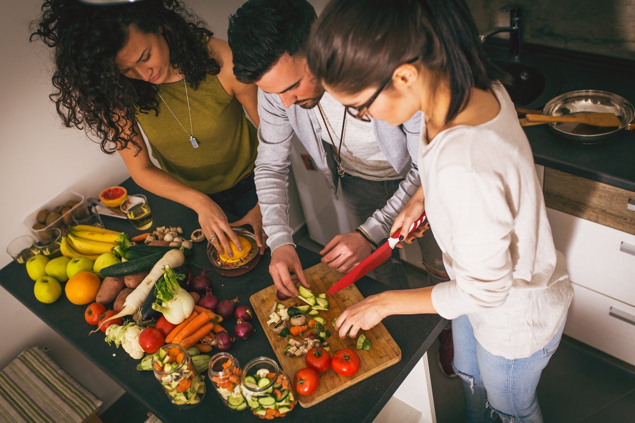 Group of friends  at the  kitchen preparing together vegetarian meal.