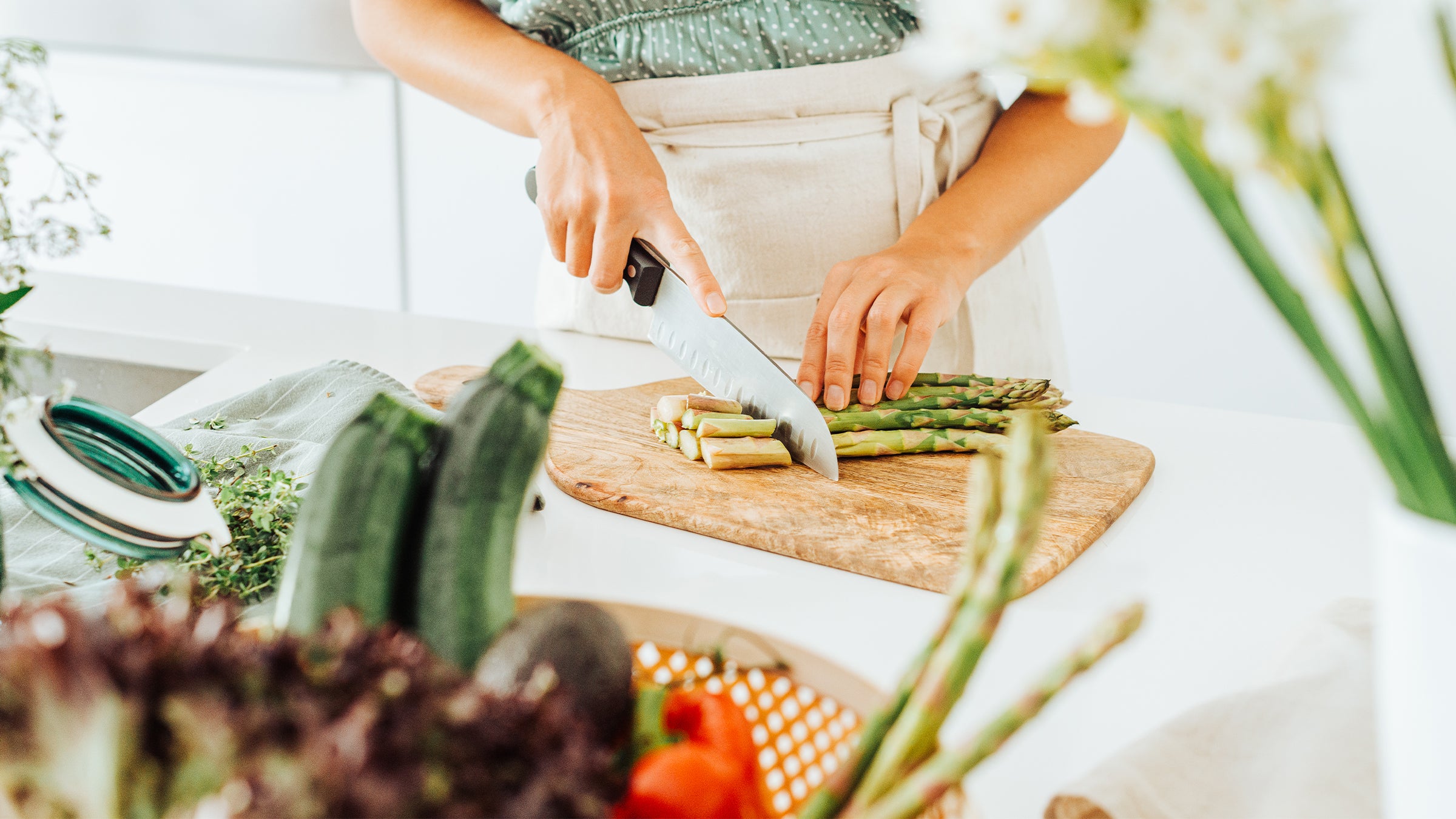 Woman chopping asparagus and other vegetables in the kitchen.