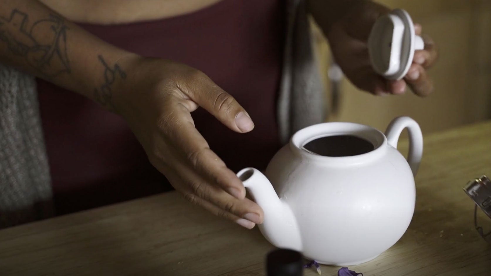Person opening a white tea kettle