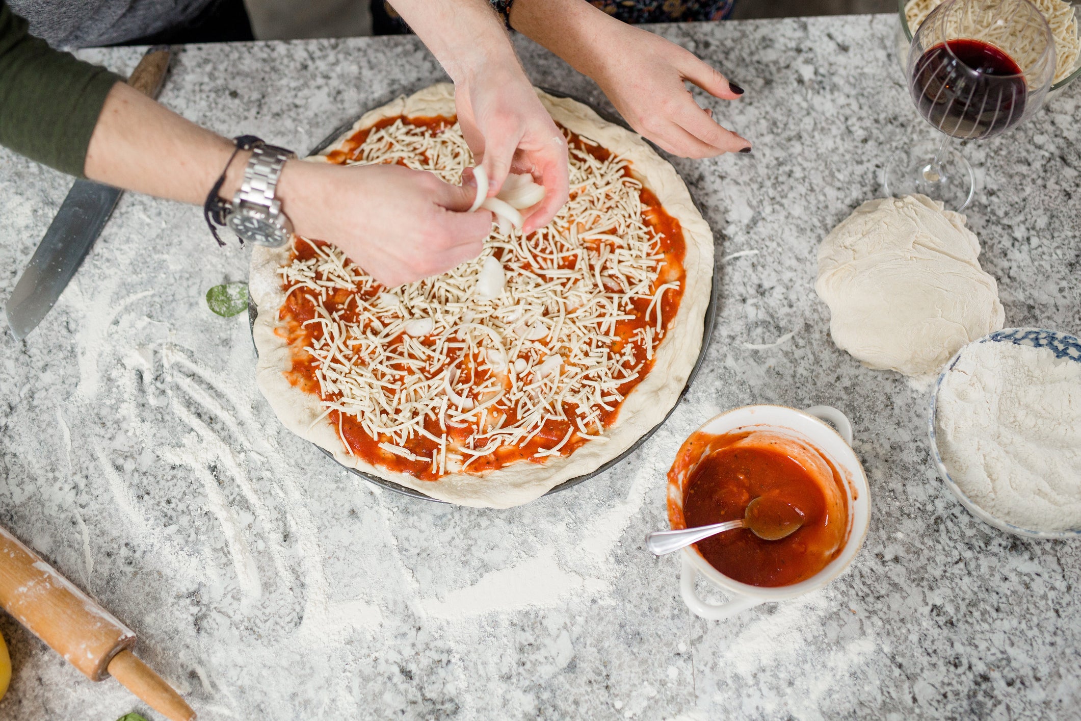 person topping a homemade vegan pizza dough