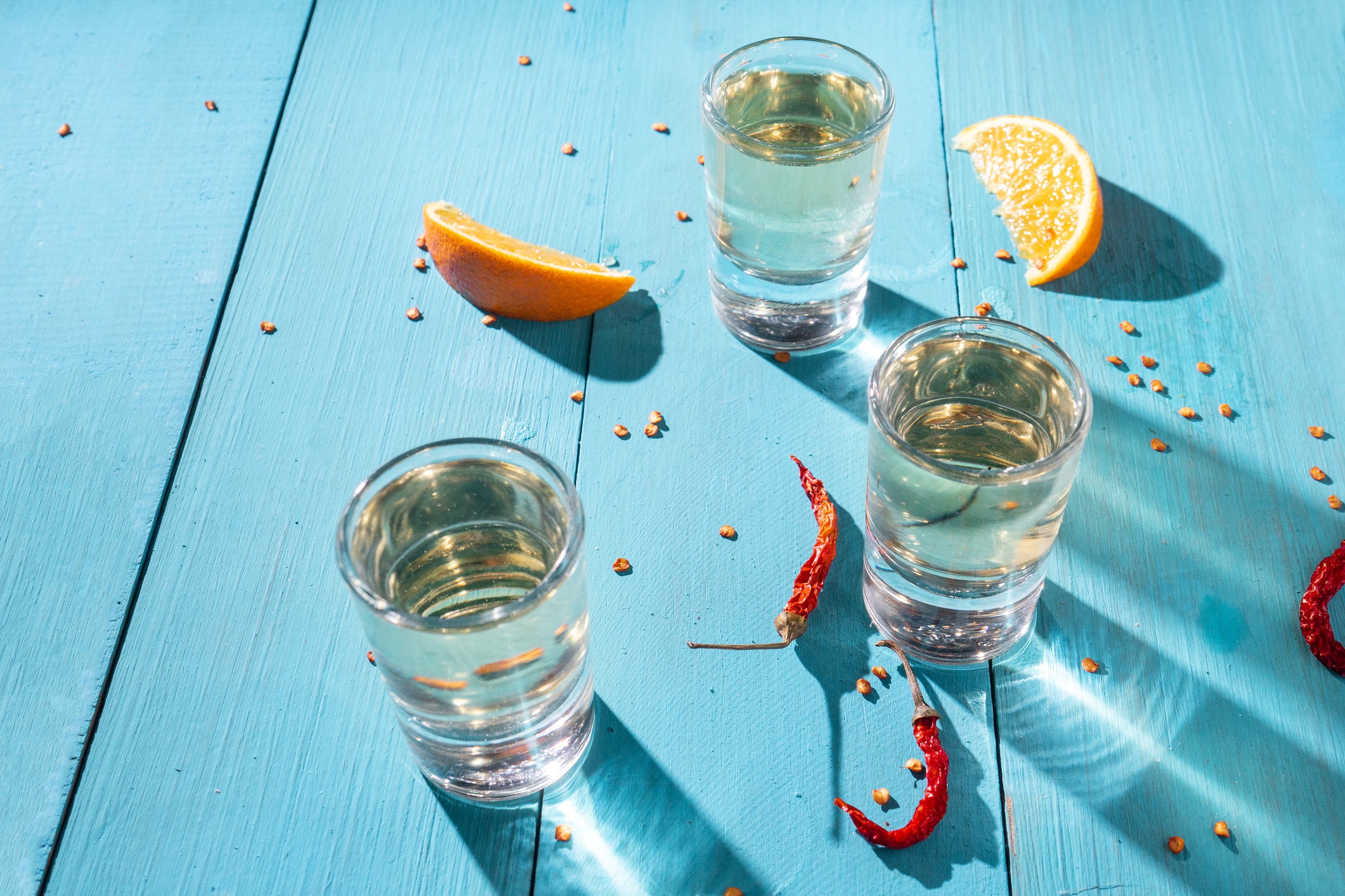 three glasses of mezcal on a blue table
