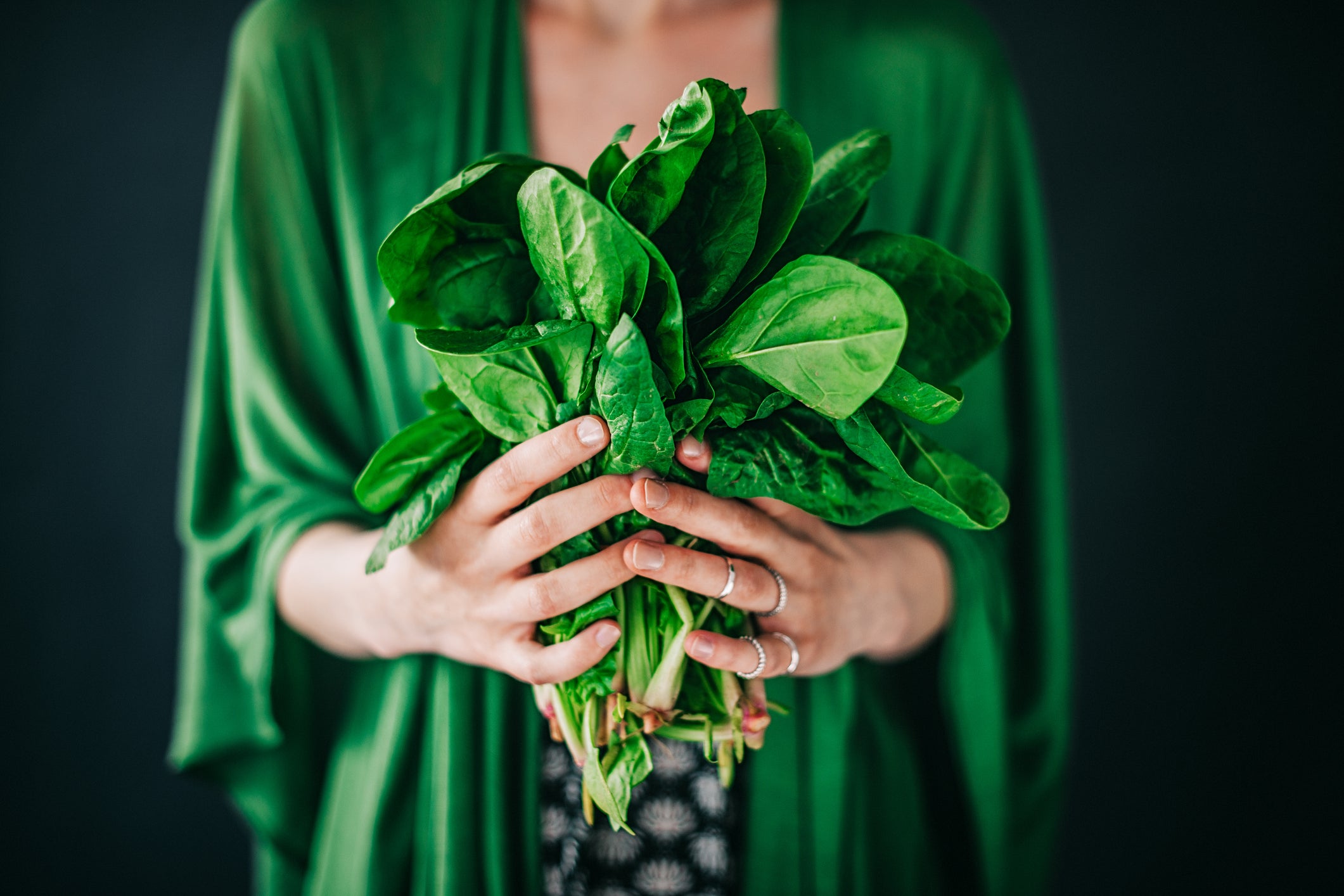 a woman holding a bunch of spinach to illustrate global spinach consumption