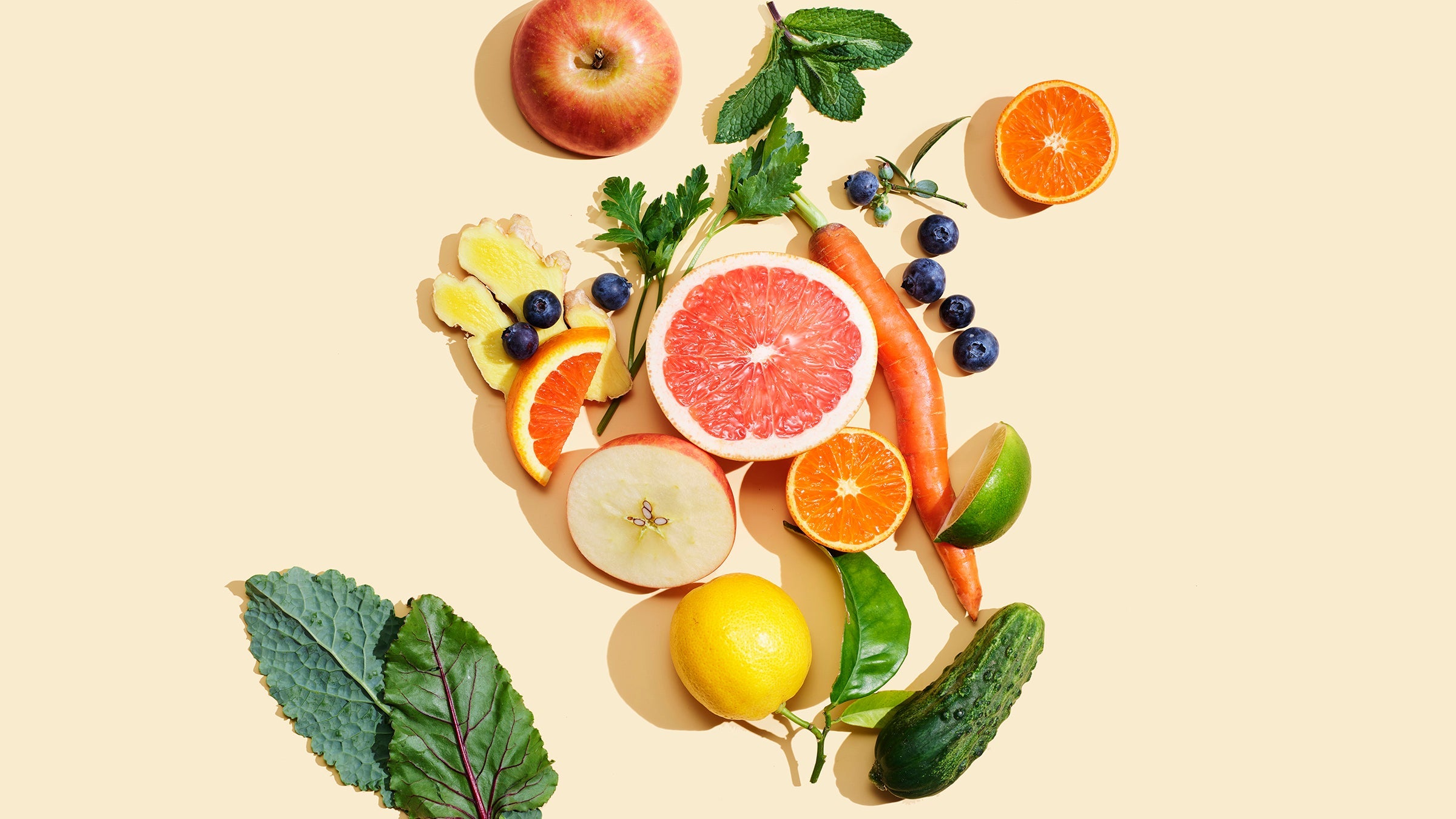 Fresh sliced fruits and leaves on peach background