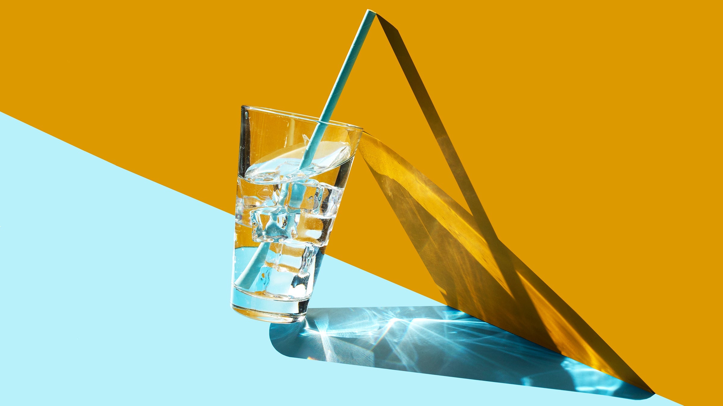 Glass of ice water on blue and yellow background to encourage one to drink more water
